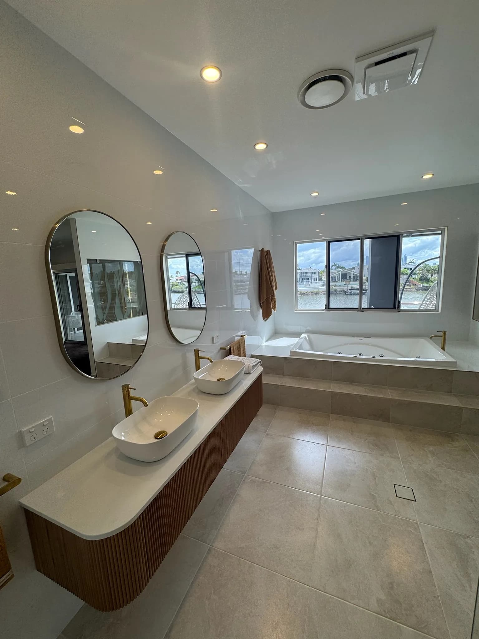A finished bathroom with twin round mirrors, stone vanity and a built in bath