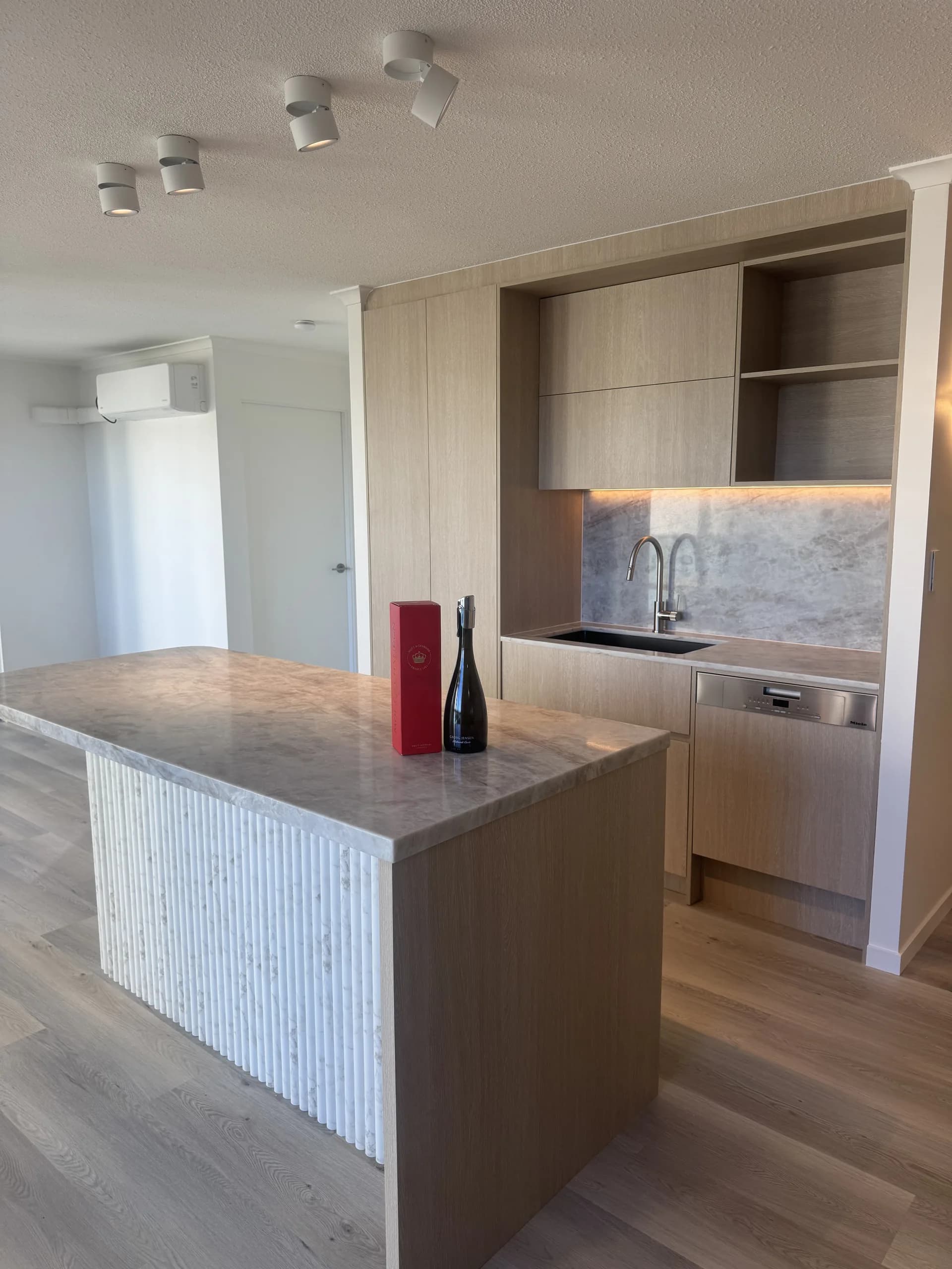A finished kitchen with stone benchtops, timber joinery and integrated appliances